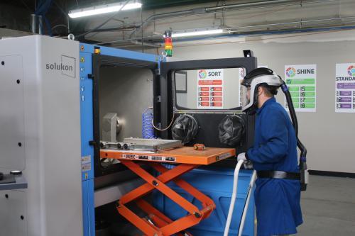 Picture of a student working on a state-of-the-art depowdering machine