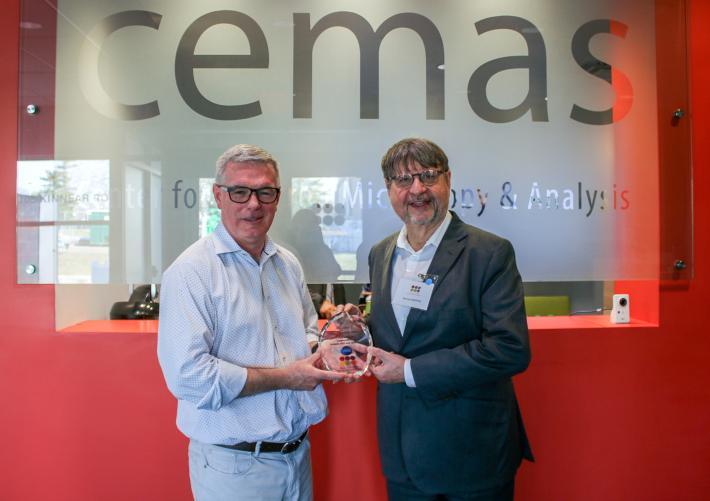 two men posing with a glass award 