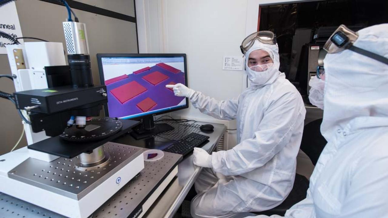 Two researchers looking at digital results on a computer screen.