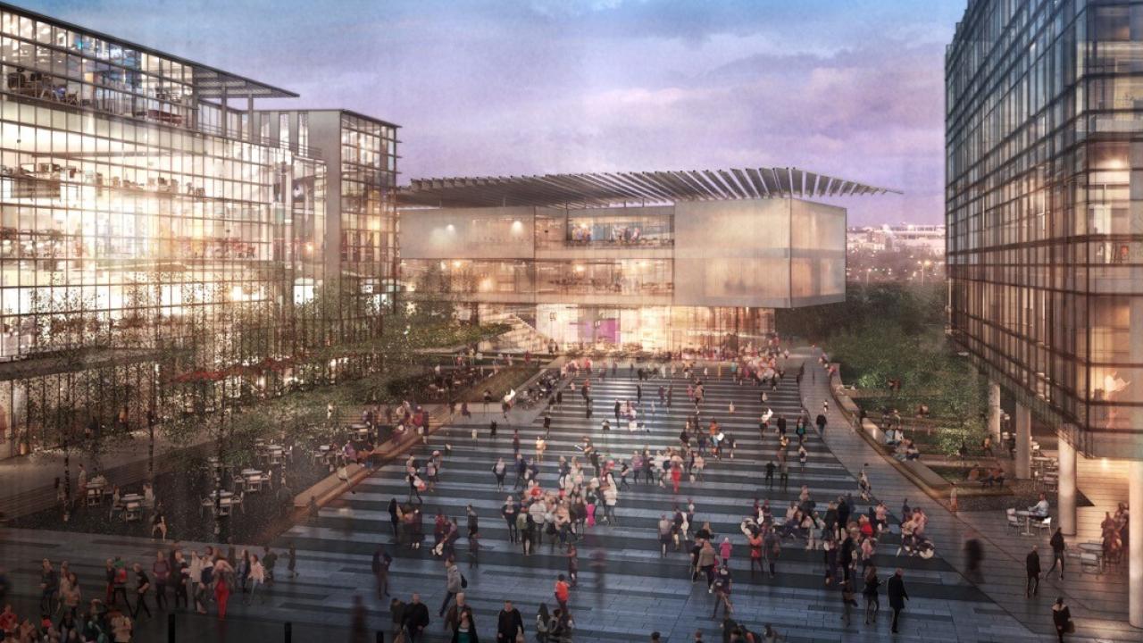 Photo of the future West Campus Innovation District well-lit, at night, with people walking around in groups.